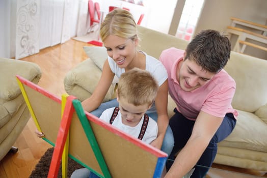 happy young family teach leassons and prepare their son for school while draw on board at home