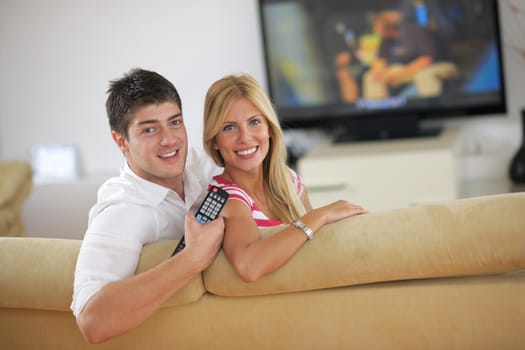 Relaxed young  couple watching tv at home in bright living room