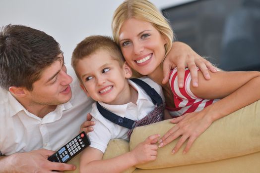 happy young family with kids in bright modern living room have fun and looking big flat lcd tv