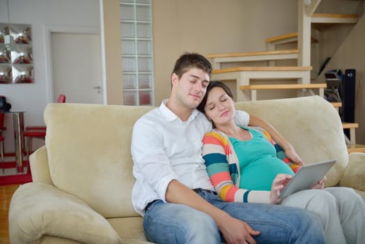 pregnant woman with her husband have fun relax and using tablet comture at modern home