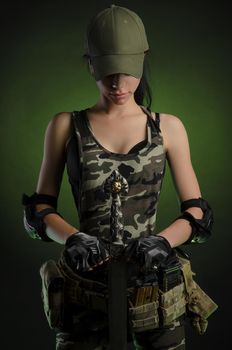 girl in military overalls airsoft posing with a gun in his hands on a dark background in the haze