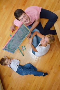 happy young family teach leassons and prepare their son for school while draw on board at home