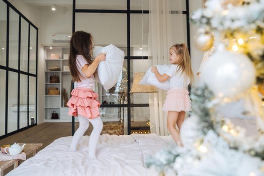 two girls playing with pillows in bedroom