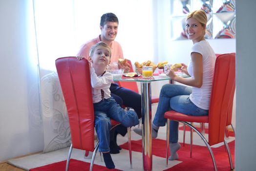 happy young family have healthy breakfast at kitchen with red details on bright morning light