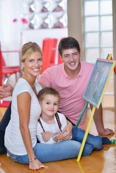 happy young family teach leassons and prepare their son for school while draw on board at home