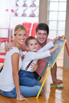 happy young family teach leassons and prepare their son for school while draw on board at home