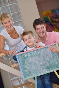 happy young family teach leassons and prepare their son for school while draw on board at home