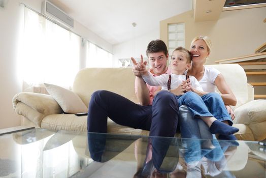 happy young family with kids in bright modern living room have fun and looking big flat lcd tv