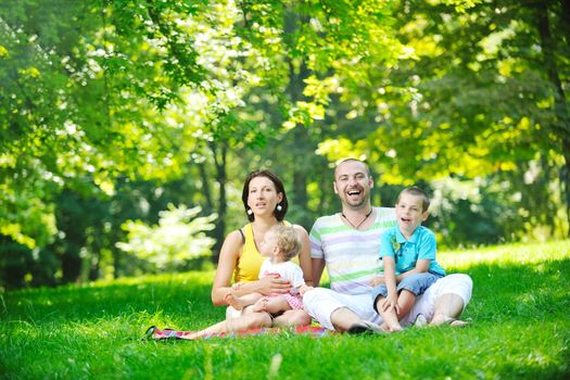 happy young couple with their children have fun at beautiful park outdoor in nature