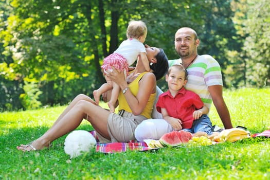 happy young couple with their children have fun at beautiful park outdoor in nature