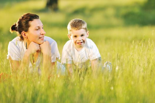 happy child and woman outdoor playing with soap bubble on meadow