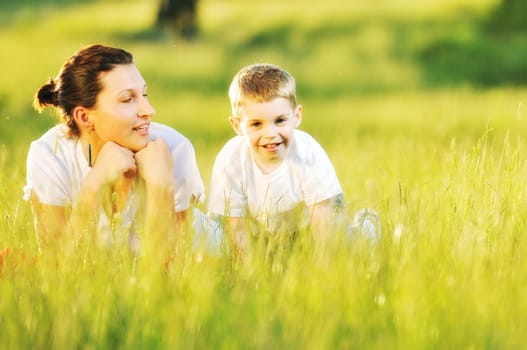 happy child and woman outdoor playing with soap bubble on meadow