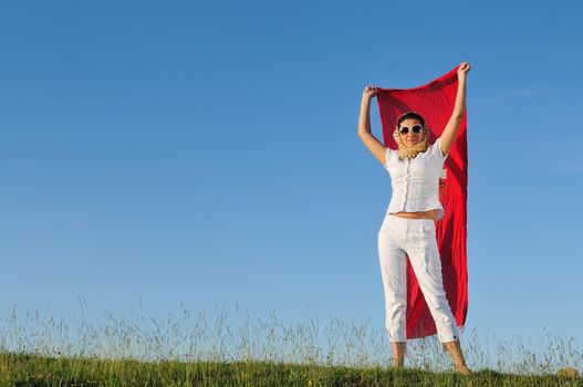 beautiful young and healthy woman run and jump on meadow at sunny day with red scarf