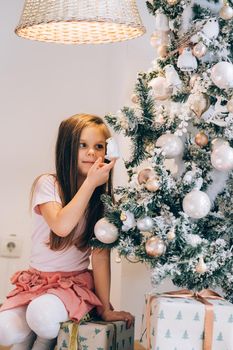 Adorable little girl decorating a Christmas tree with baubles