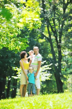 happy young couple with their children have fun at beautiful park outdoor in nature