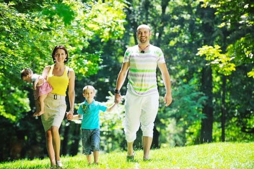 happy young couple with their children have fun at beautiful park outdoor in nature