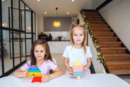 Photo of two little girls playing at the table on the camera indoors