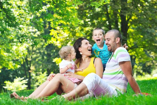 happy young couple with their children have fun at beautiful park outdoor in nature