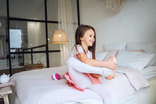 little girl on the bed takes off her shoes at room