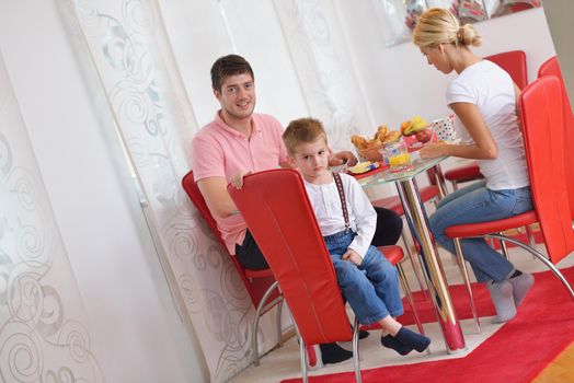 happy young family have healthy breakfast at kitchen with red details on bright morning light