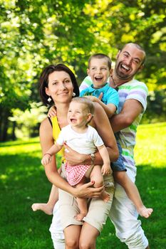 happy young couple with their children have fun at beautiful park outdoor in nature