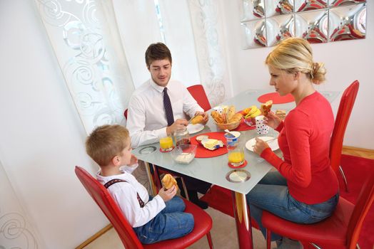 happy young family have healthy breakfast at kitchen with red details on bright morning light