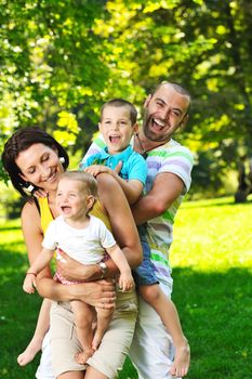 happy young couple with their children have fun at beautiful park outdoor in nature