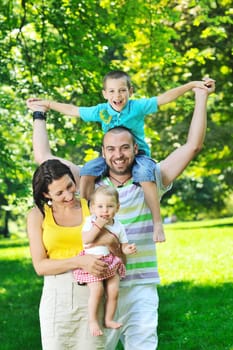 happy young couple with their children have fun at beautiful park outdoor in nature