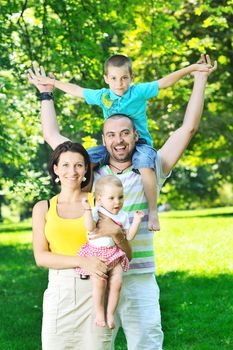 happy young couple with their children have fun at beautiful park outdoor in nature