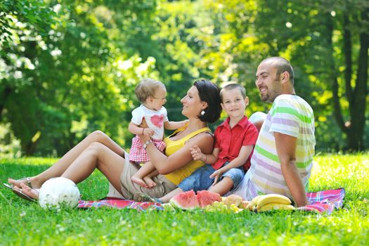 happy young couple with their children have fun at beautiful park outdoor in nature