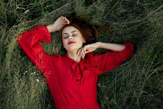 woman in red dress lies on the grass nature freedom summer. High quality photo