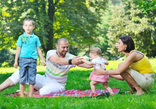 happy young couple with their children have fun at beautiful park outdoor in nature