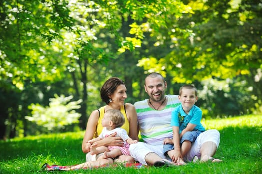 happy young couple with their children have fun at beautiful park outdoor in nature