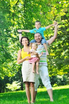 happy young couple with their children have fun at beautiful park outdoor in nature