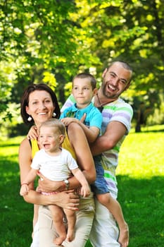 happy young couple with their children have fun at beautiful park outdoor in nature