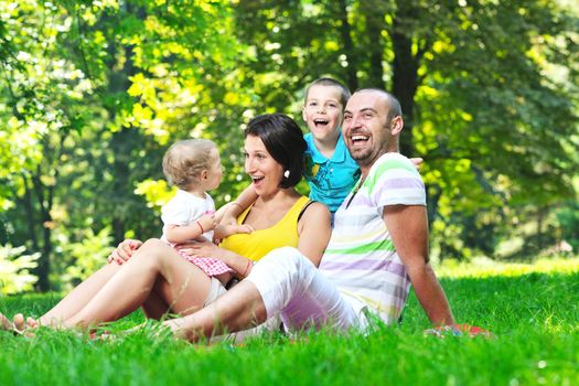 happy young couple with their children have fun at beautiful park outdoor in nature