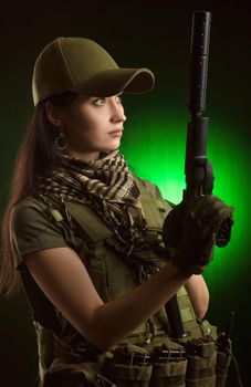 girl in military special clothes posing with a gun in his hands on a dark background in the haze