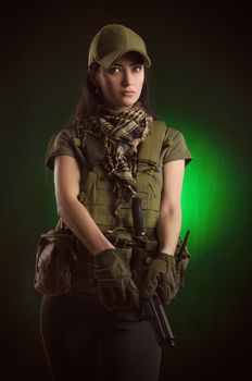 girl in military special clothes posing with a gun in his hands on a dark background in the haze