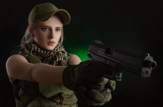 the girl in military special clothes posing with a gun in his hands on a dark background in the haze