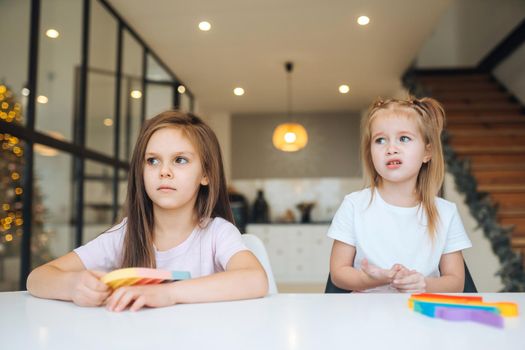 Photo of two little girls playing at the table on the camera indoors