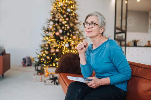 Grandma sits on the couch writing something in a note at home