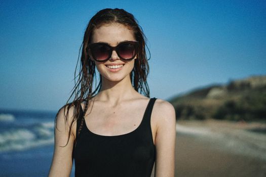 pretty woman in black swimsuit posing sun walking on the beach. High quality photo