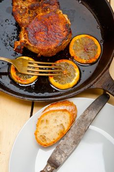 pork chop seared on iron skillet with lemon and spices seasoning