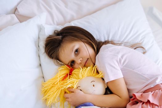 health and beauty concept - little girl with toy sleeping at home
