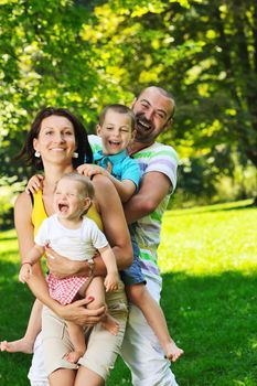 happy young couple with their children have fun at beautiful park outdoor in nature