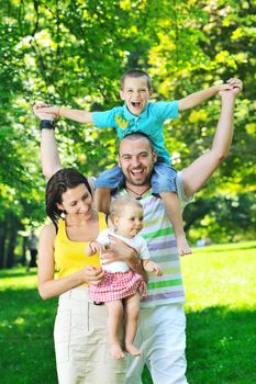 happy young couple with their children have fun at beautiful park outdoor in nature