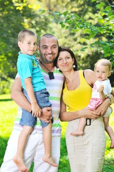 happy young couple with their children have fun at beautiful park outdoor in nature