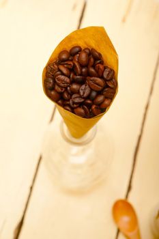 espresso coffee beans on a paper cone cornucopia over white background