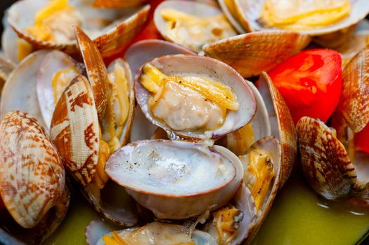 fresh clams stewed on an iron skillet over wite rustic wood table 