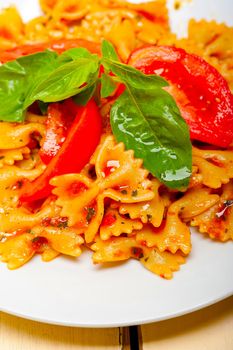 Italian pasta farfalle butterfly bow-tie with tomato basil sauce over white rustic wood table